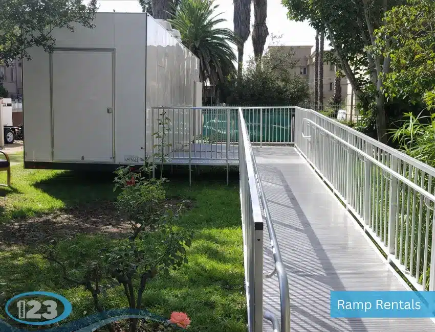 ADA-compliant metal accessibility ramp with safety handrails leading to a temporary modular building entrance.